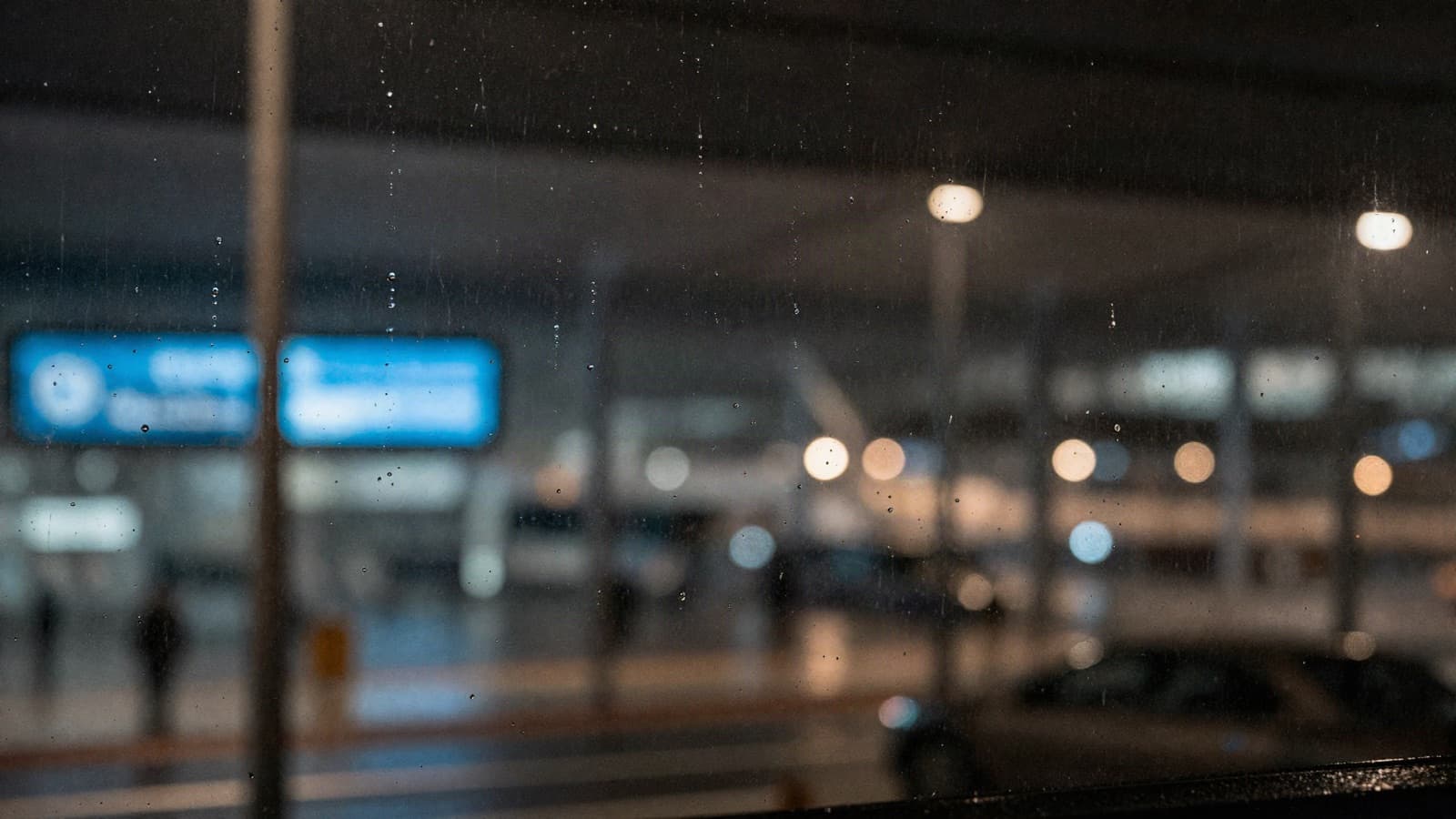 Rain running down a terminal window at night, apron lights blurred behind it.